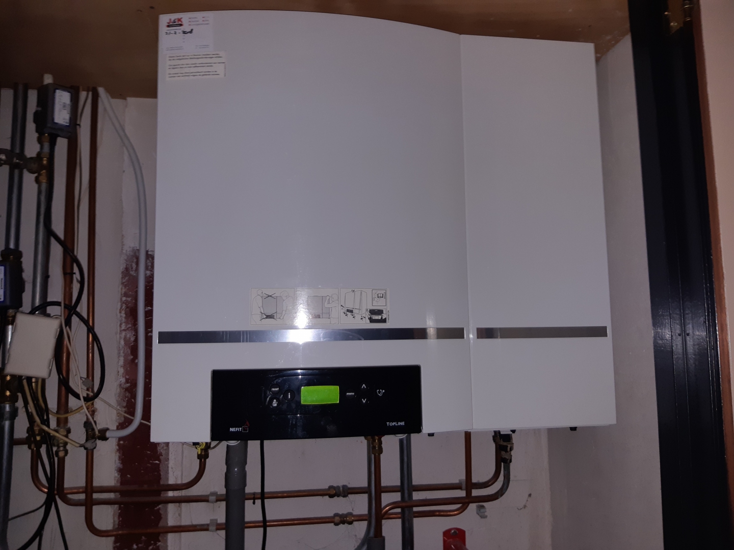 De aangeboden Nefit Topline cv-ketel, nog aan de muur gemonteerd met koperen leidingwerk eronder